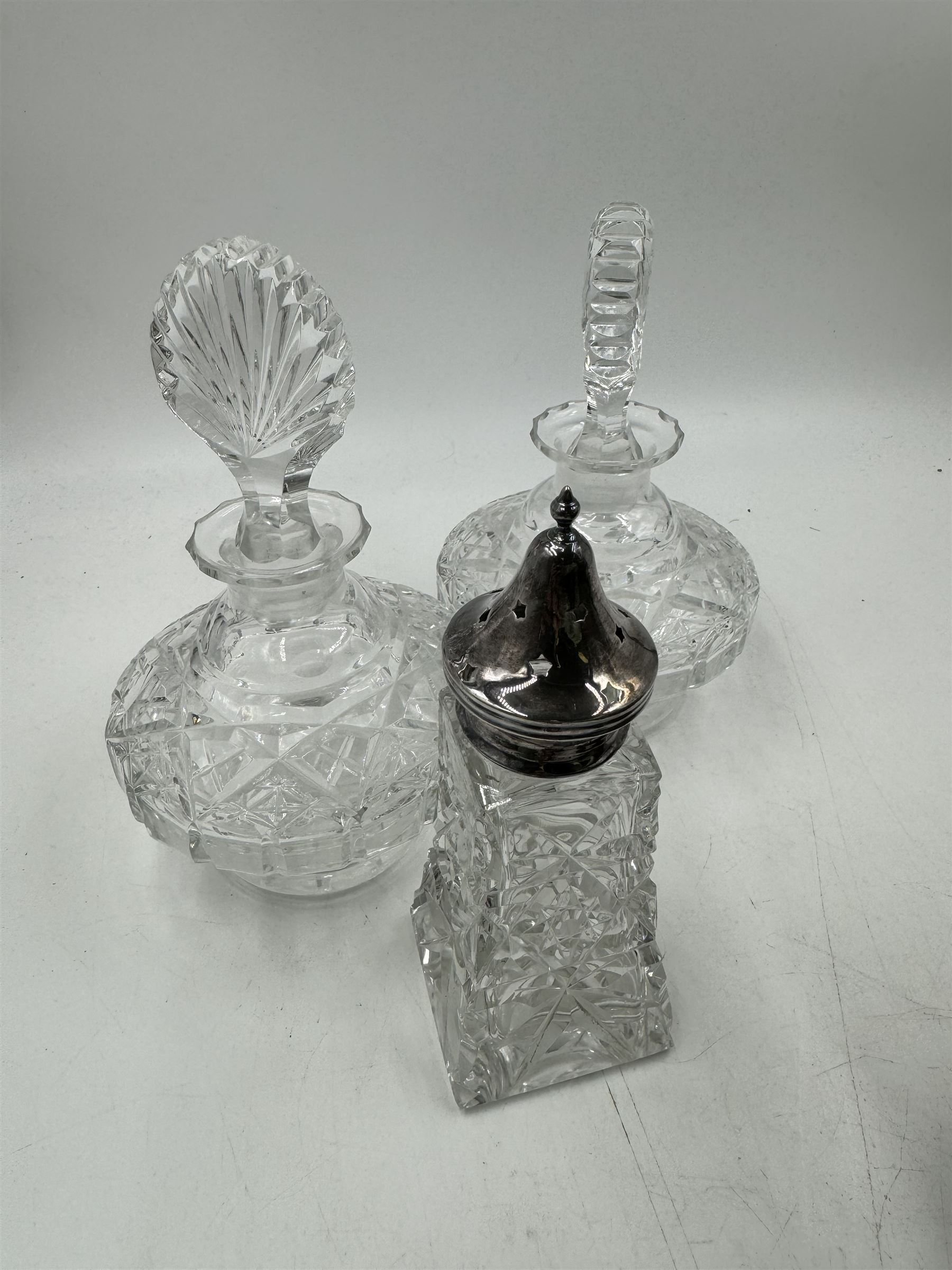 Two cut glass decanters, together with a faceted red glass bottle, cut glass sugar caster with pierced star cover, silver plated stirrup cup, chainmail scarf, plaster ships plaque and a walnut box with mother of pearl cartouche