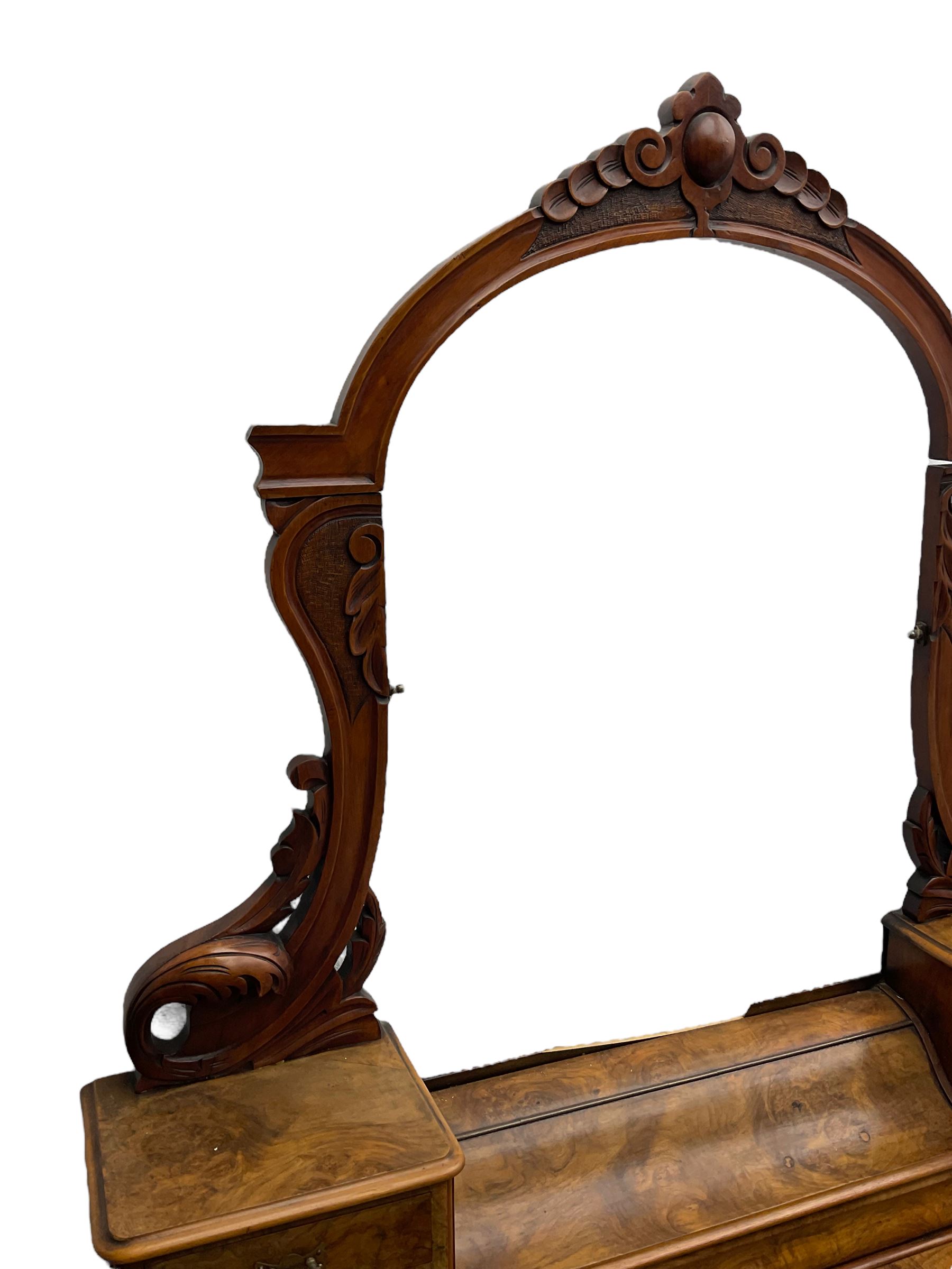 19th century figured walnut dressing table, the raised bevelled mirror back in carved foliage frame with scrolled terminals, fitted with central hinged compartment flanked by small trinket drawers, serpentine moulded top over single frieze drawer, on cabriole supports united by a platform base