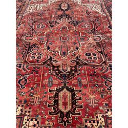 Persian Heriz red ground carpet, large central eight point medallion with projecting palmettes surrounded by small geometric motifs, decorated profusely with hooks, rosettes and animals, the busy border decorated with stylised foliate motifs within guard stripes 