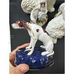 Staffordshire and Staffordshire style figures, to include a chained hound upon a blue oval base in the manner of Samuel Alcock, two pairs of seated Spaniels, a pair modelled as male figure and milk maid with cows, pair of recumbent Greyhounds, etc.