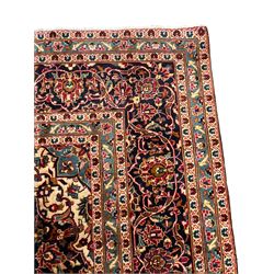 Persian Kashan crimson ground carpet, floral pattern pole medallion surrounded by trailing branches with foliate motifs and palmettes, scrolling border decorated with stylised plant motifs, within multiple guard stripes