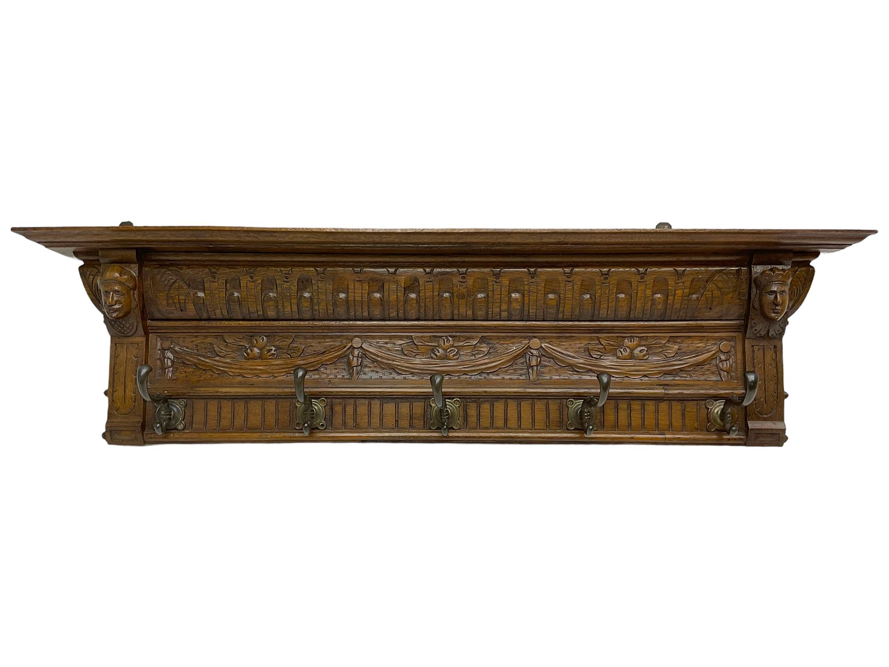 Late 20th century carved oak wall hanging coat rack, projecting moulded lintel over arcade carved frieze, flanked by two carved masks, fitted with five foliate cast hooks