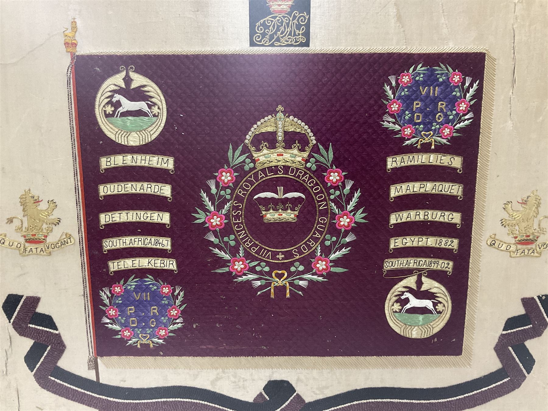 Commemorative Military needlework, headed 'VII Princess Royal's Dragoons Guard, the central flag has the regimental title, surrounded by a Union wreath of roses, thistles and shamrocks, topped with a crown, the Hanoverian white horse features in two corners, framed H58cm, L73cm