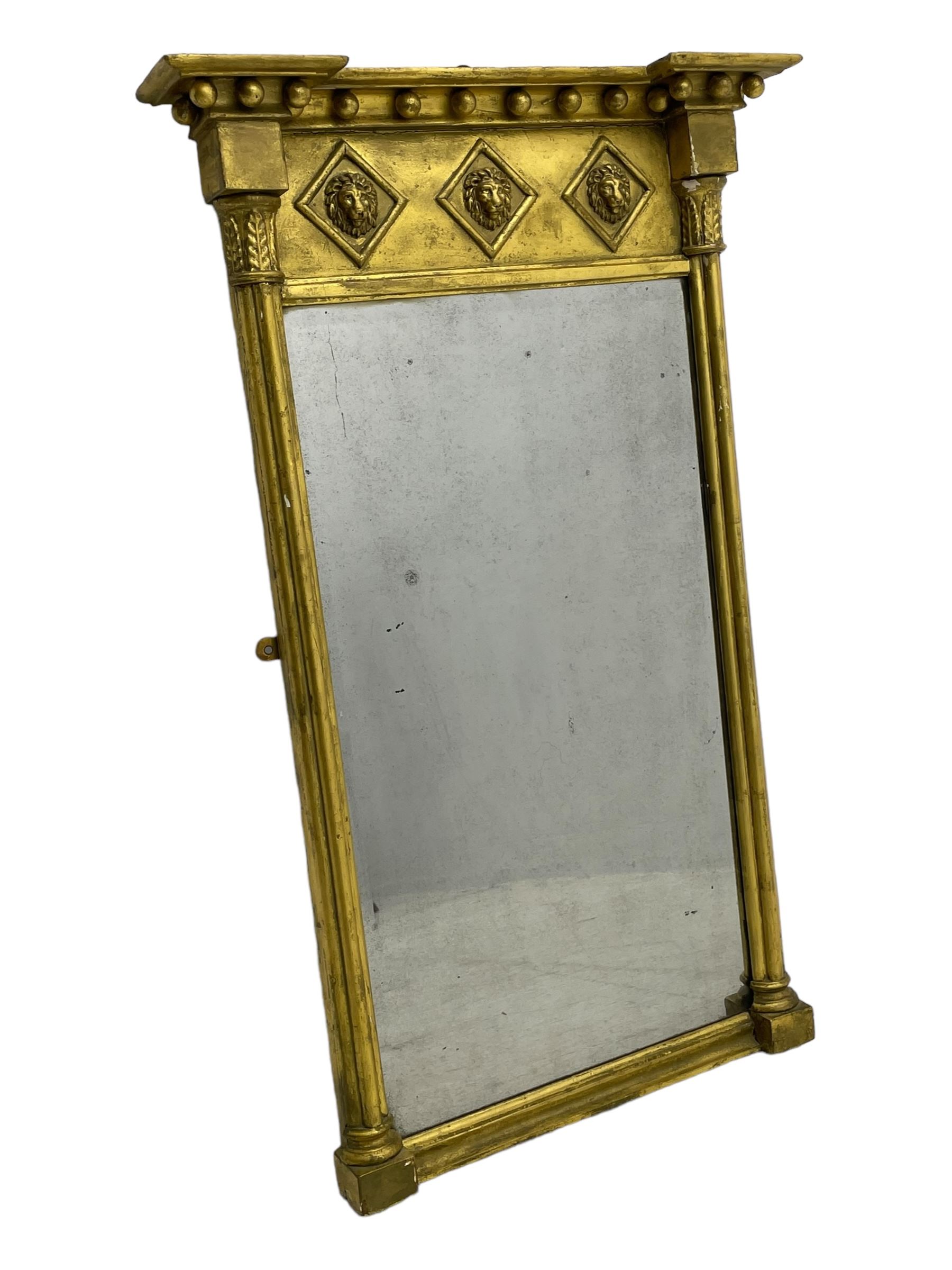 Regency giltwood and gesso pier mirror, projecting moulded cornice with globular mounts, the frieze decorated with three lion masks within lozenges, cluster column uprights with leaf decorated capitals, bevelled mirror plate