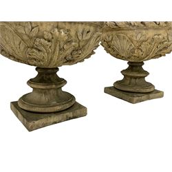 Pair of composite stone garden urn planters, acanthus leaf garland rim over foliate decorated body, stepped foot on square base