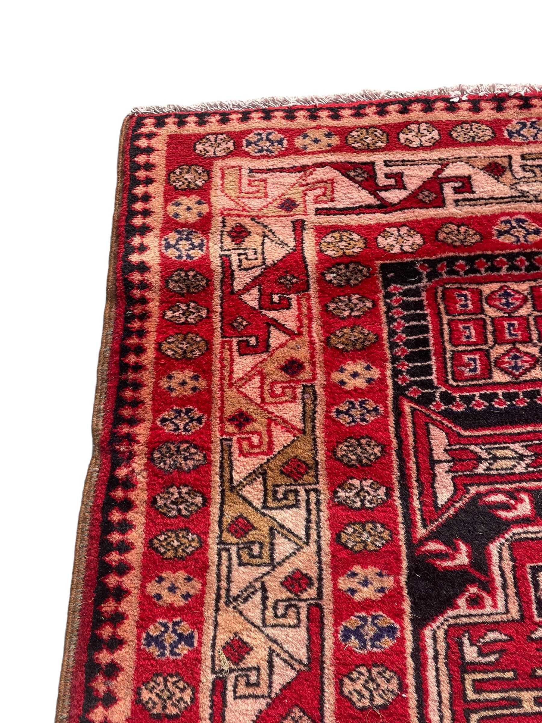 Persian Hamadan indigo and crimson ground rug, the field filled with three shaped medallions, overall geometric design, decorated with sandikli and hac motifs, geometric main border with repeating hooked motifs, within guard stripes decorated with small flower heads, outer crenelated fence band 