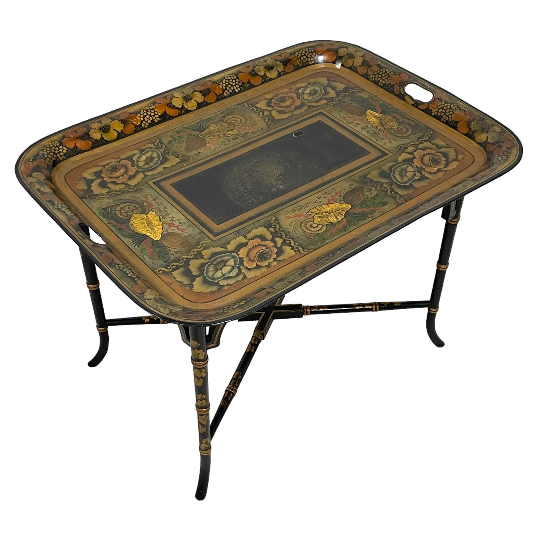 19th century tole ware tray of rectangular form, decorated with Japanese inspired floral motifs and gilt shells, with pierced handles, the associated ebonised and gilt stand, raised on ring turned splayed supports united by X-stretcher, decorated with gilt foliage