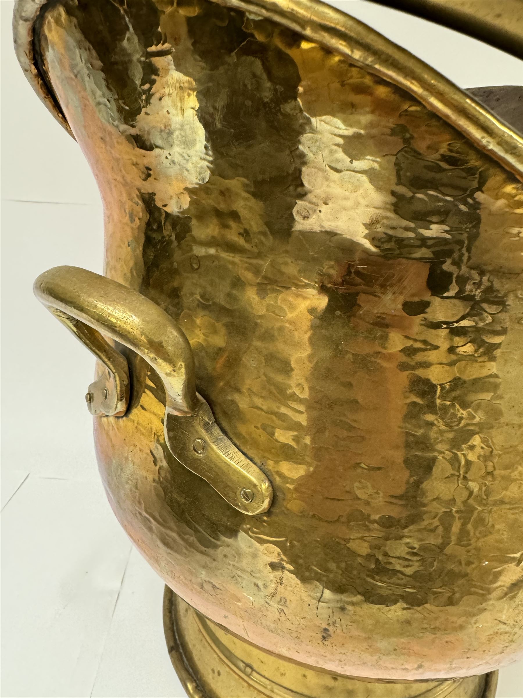 Middle eastern copper bucket, with chased and embossed band of animal decoration, together with a copper jardinière embossed with floral panels, copper plate with embossed leaf motif and two brass helmet shaped coal scuttles, bucket H26cm