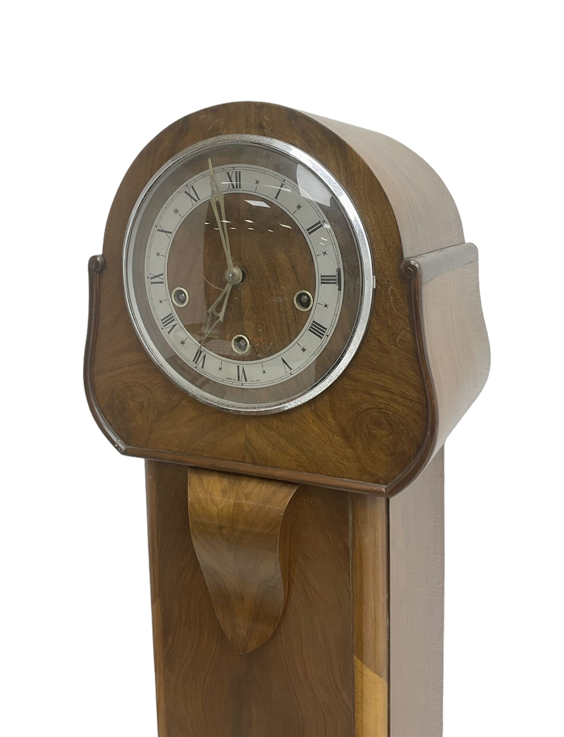 English - 1950's walnut 8-day quarter chiming grandmother clock, rounded top with a splayed base on bracket feet, wooden dial centre with a silvered chapter dial, chrome hands and roman numerals enclosed within a chrome bezel, three train going barrel movement chiming the quarters and hours on 8 gong rods. With pendulum.