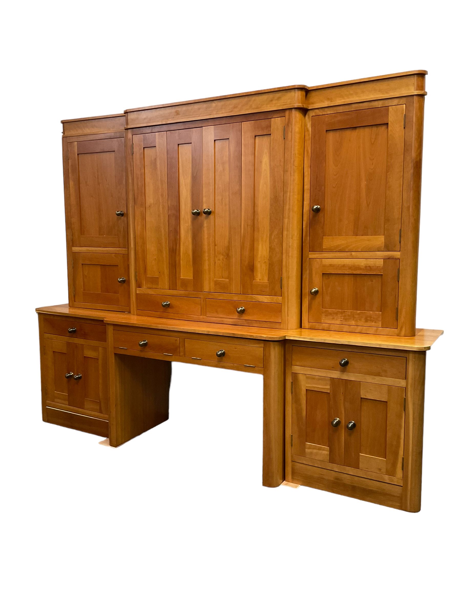 Large contemporary cherry wood break-front wall unit, the banded cornice over double cupboard with bifold doors and two drawers, flanked by four single cupboards, the base fitted with four drawers over four cupboards