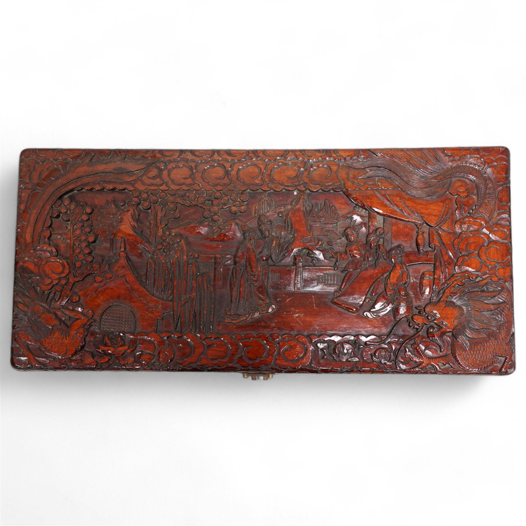 Chinese heavily carved and lacquered camphor wood blanket chest, rectangular hinged top, carved all-over with traditional figural and pagoda scenes with exotic birds, enclosed by a border of stylised clouds