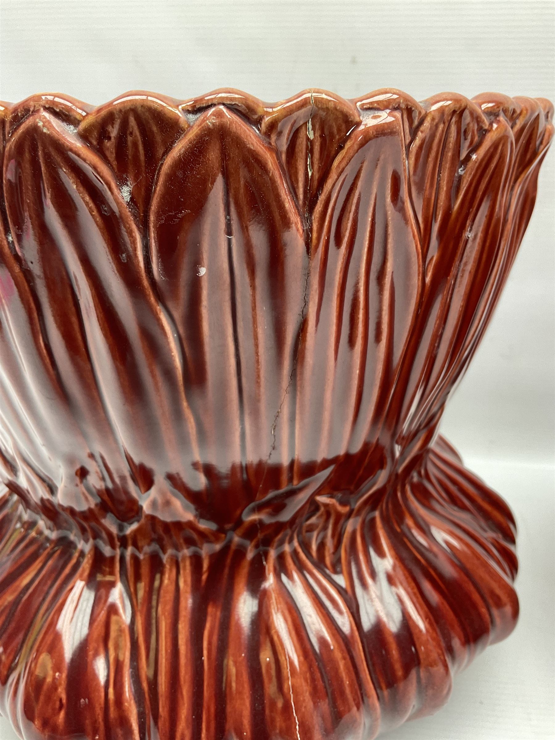 Two Bretby jardinieres, the first example with geometric hexagonal decoration in a red glaze, the second moulded as a flower head, in red glaze with yellow glaze to interior,  both with impressed marks beneath, tallest H25.5cm