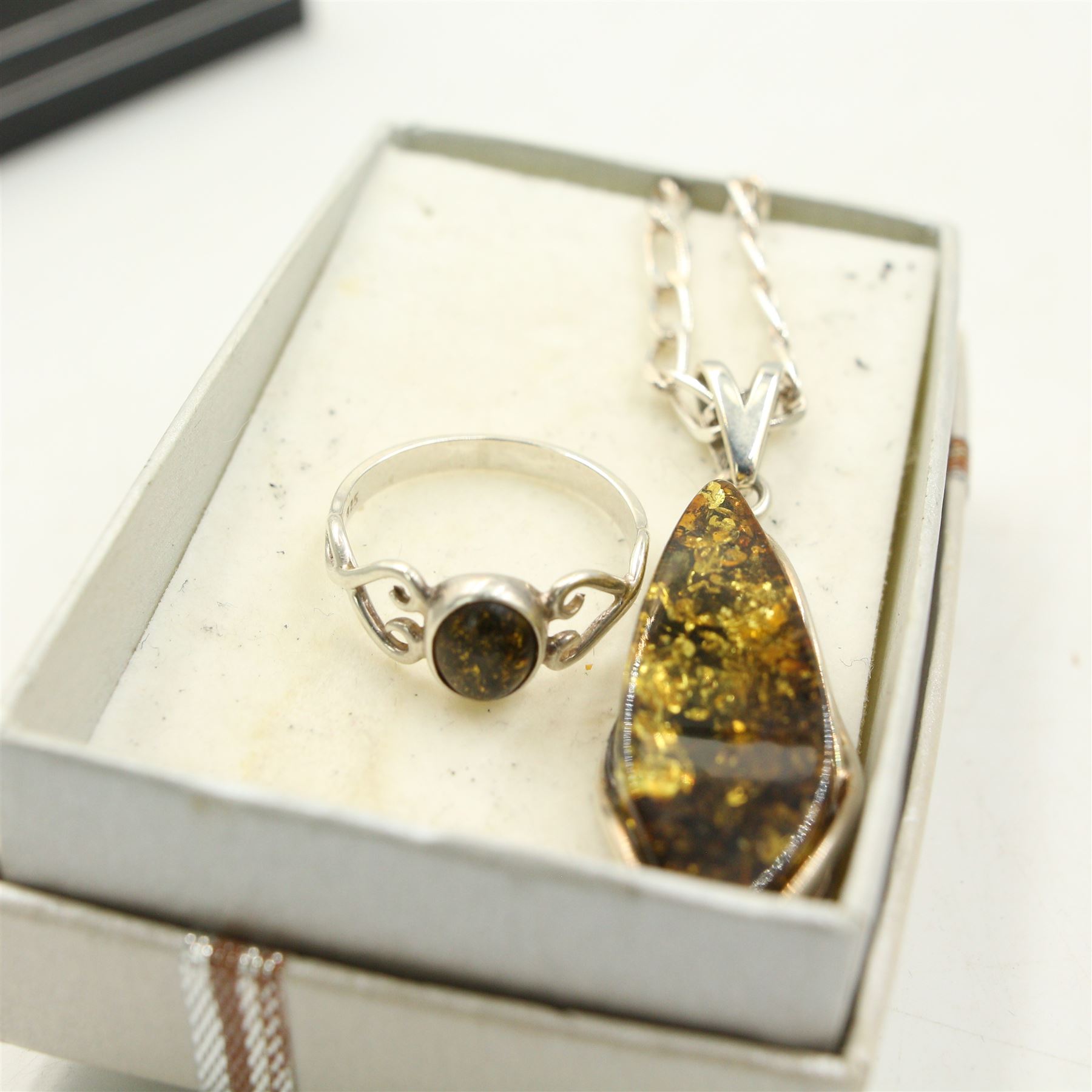 Group of silver amber jewellery, including three amber pendant necklaces, an amber bracelet, amber brooch and two amber rings