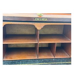 Edwardian inlaid mahogany roll-top desk, cylindrical lid enclosing fitted interior with pigeonholes, drawers and retractable writing surface, over two drawers with brass pull handles, on tapered supports with brass and ceramic castors