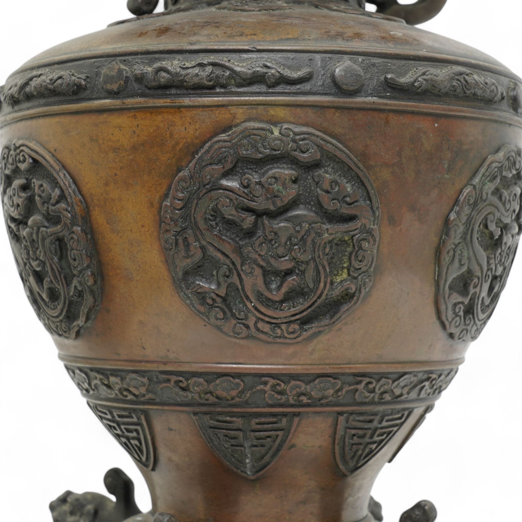 Late 19th/ early 20th century Japanese bronze Usubata vase, the flared top over two Phoenix cast handles, the ovoid body decorated in relief with mythical creatures within roundels, on four open mouth lion mask and scroll supports, H43cm x W24cm 