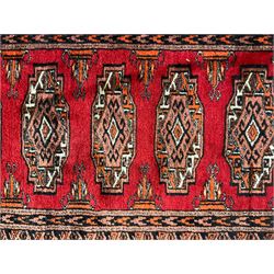 Persian Bokhara dark amber round rug, crimson field with six Gul motifs, surrounded by a guarded border with geometric design (124cm x 70cm); together with another similar in amber and red (101cm x 63cm) (2)