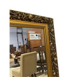 Large rectangular gilt framed wall mirror, decorated with trailing leafy branches and flowerheads, bevelled glass plate 