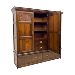 Late Victorian walnut triple wardrobe, projecting moulded cornice over central bevelled mirror door and flanking panelled doors, the top panels carved with fluted fans and stylised leaf motifs, the interior fitted with three linen slides, two drawers and hanging space, two long drawers to base, reed moulded uprights and vertical fluted horizontal rails 