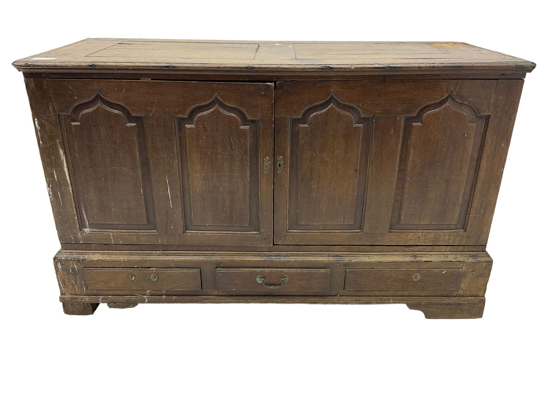 Georgian oak converted mule chest, rectangular plank top over two cupboards with arched Gothic motif panels enclosing storage area with shelves, the base with three drawers with pull handles, on shaped bracket feet