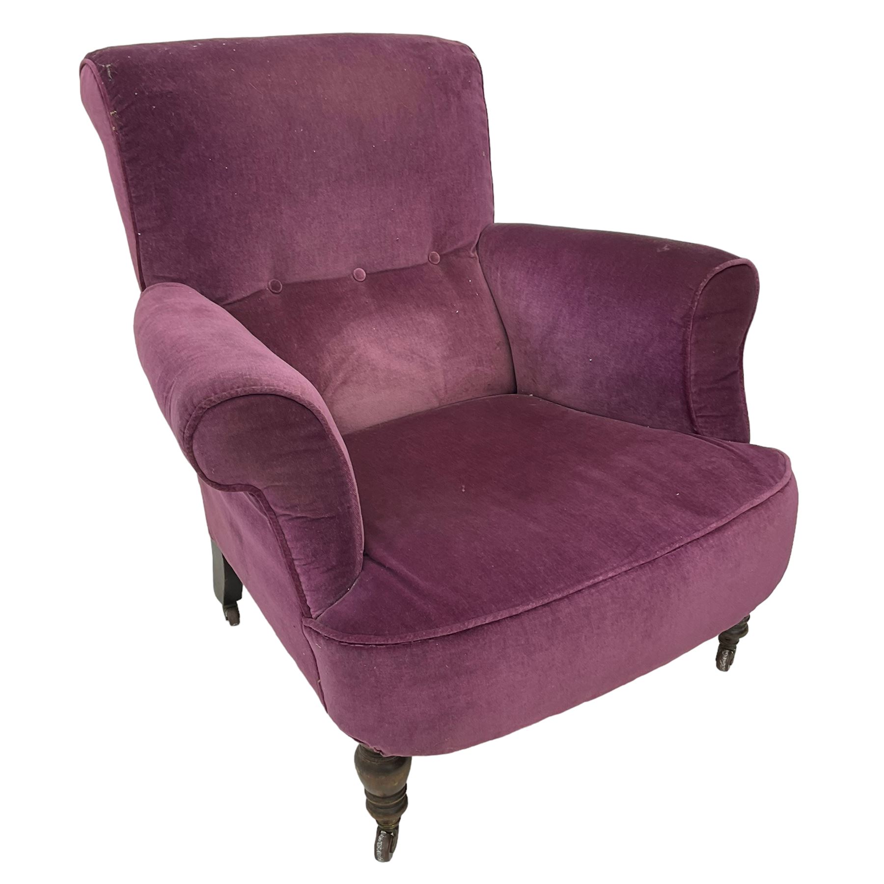 Late Victorian upholstered armchair, in deep purple velvet fabric, buttoned backrest, rolled arms, on splayed back and turned front supports with castors