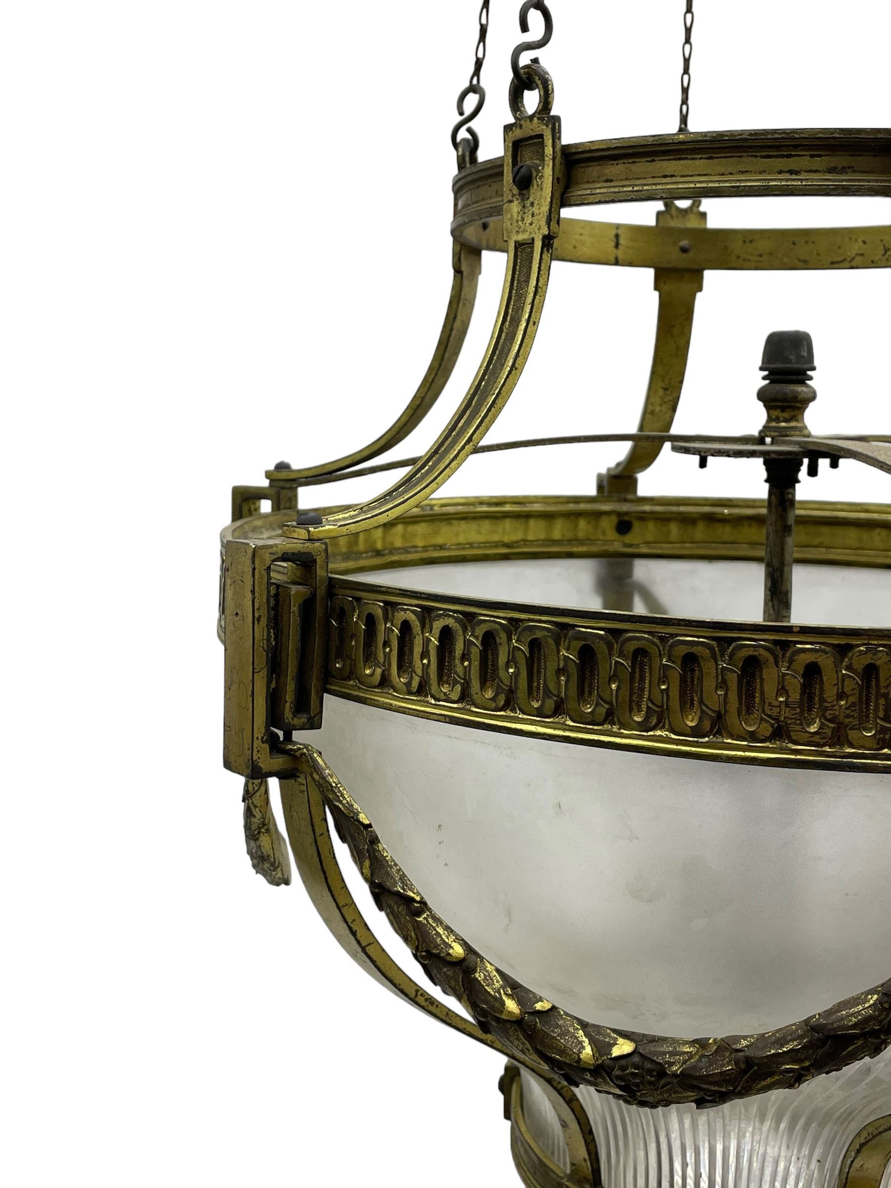 Edwardian brass ceiling light of circular bulbous form, moulded upper band over a guilloche cast central band united by shaped strapping, decorated with fruiting foliage festoons, fitted with frosted and vertical bevelled glass bowl, acanthus cast finial 