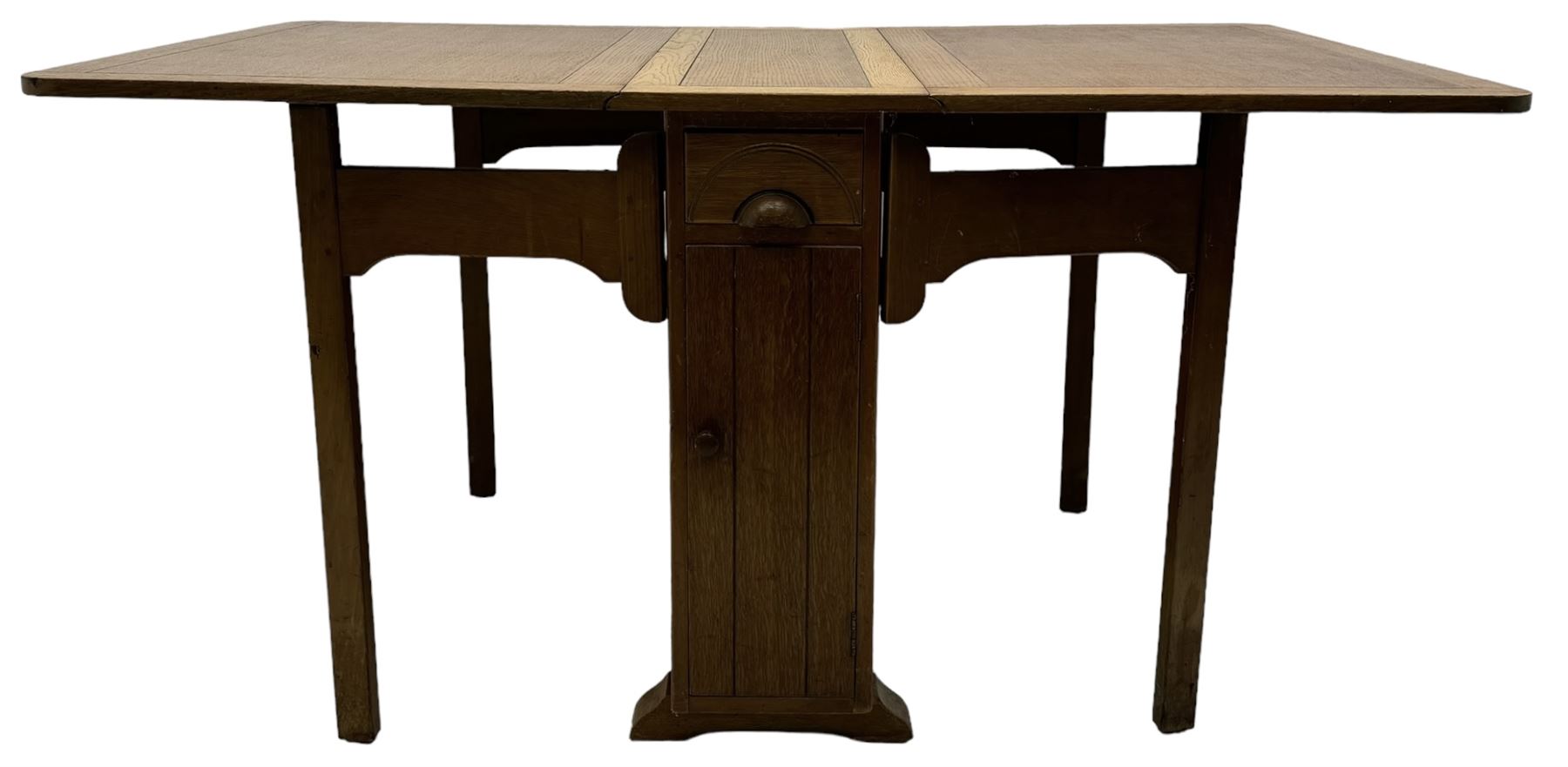 Early 20th century oak drop-leaf table, in the style of Harris Lebus, featuring rectangular top over central pedestal base, with two drawers and two cupboards, on gateleg supports