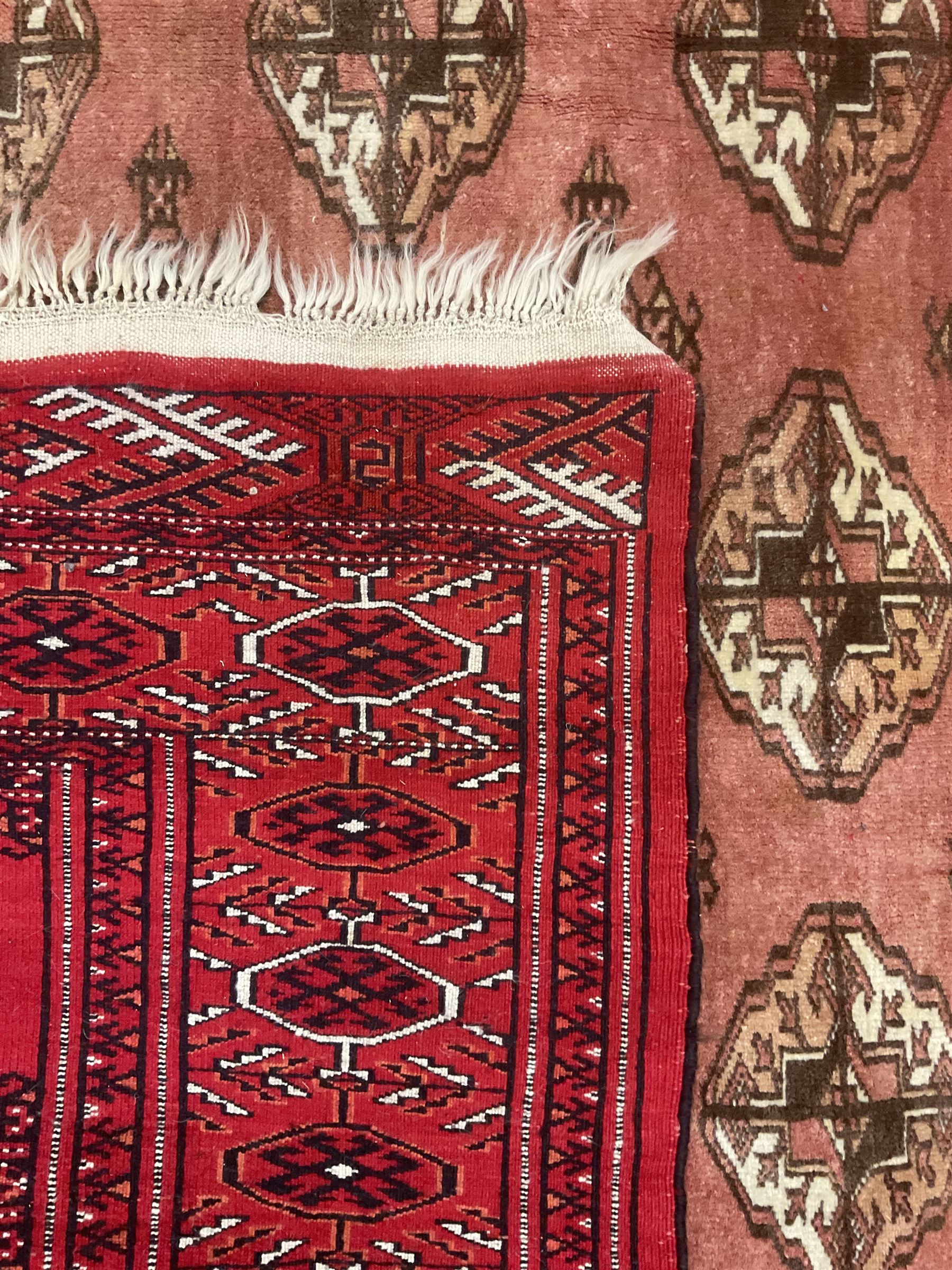 Afghan Bokhara red ground rug, the field decorated with five rows of Gul motifs, guarded border decorated with lozenges and geometric pattern 