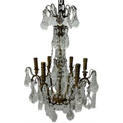 India Jane Interiors - brass and crystal six-branch chandelier, each branch holds a single candle-style bulb holder detailed with scrolling design, the chandelier is adorned with numerous crystal pendants and octagonal beads, which hang from each arm and from the cut crystal central column