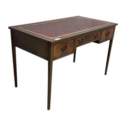 Mid-to-late 20th century mahogany writing desk, the rectangular top with a tooled red leather insert bordered with gilt detailing, three cock-beaded drawers with brass handles, the narrow central drawer flanked by two wider drawers, standing on square tapered legs