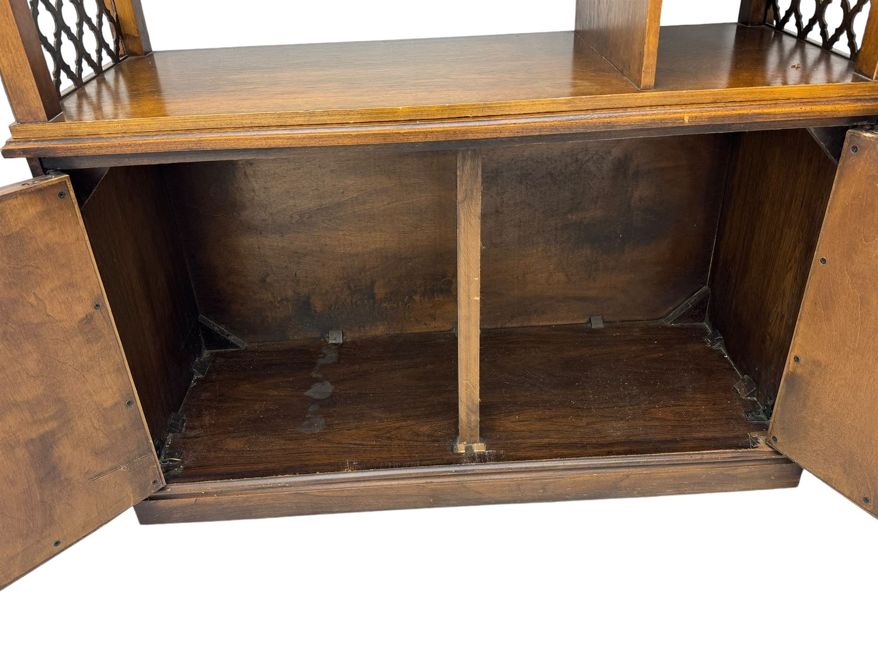 Mid 20th century oak bookcase cupboard, projecting cornice over three open shelves with subdivided sections and latticework uprights, two doors to the base with floral and scrollwork carvings and central brass handles, resting on a moulded plinth base