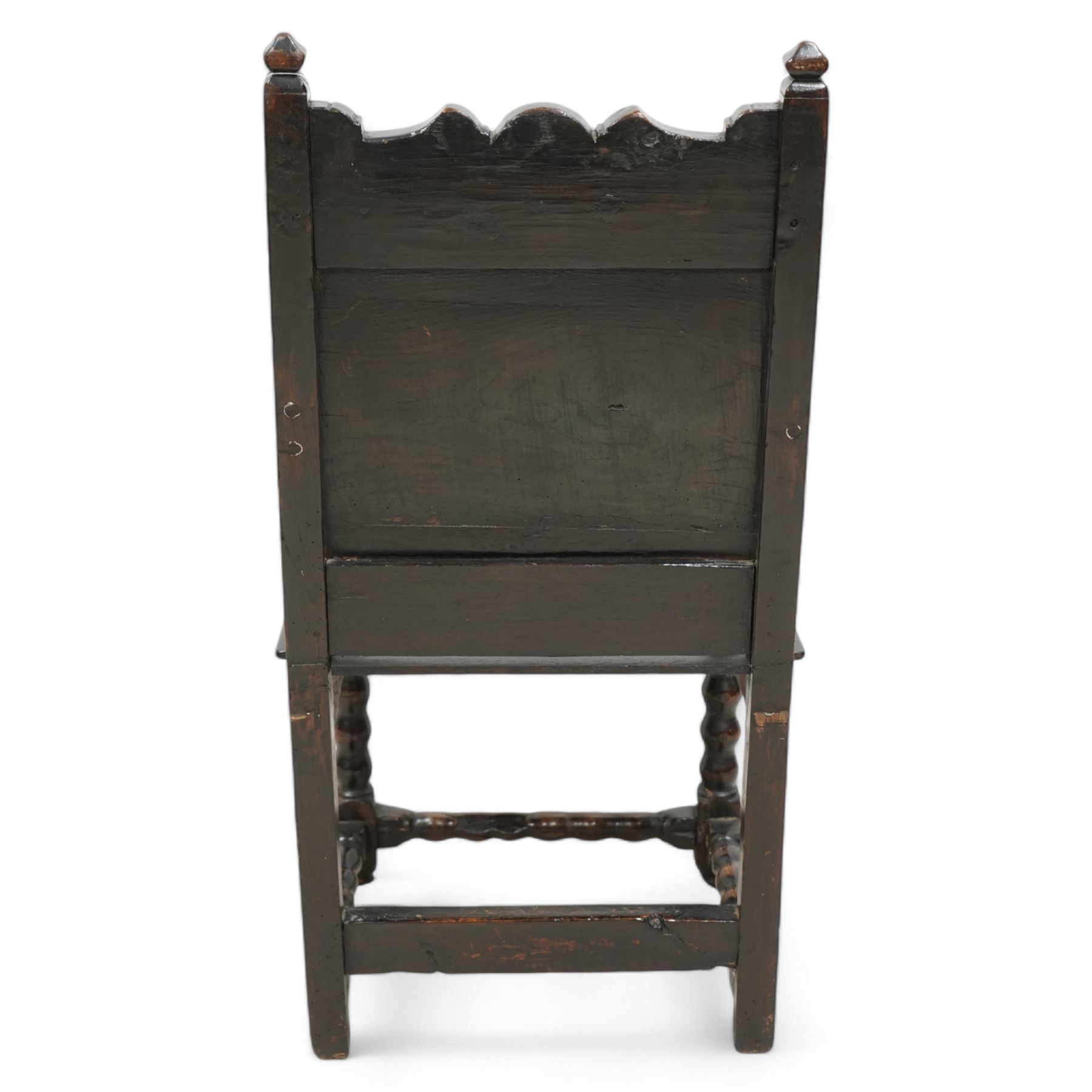 17th century and later oak wainscot chair, shaped cresting rail over panelled back, down sweeping dished arms over plank seat, on bobbin turned supports united by bobbin turned stretchers 