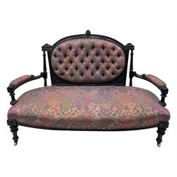 Late Victorian ebonised oak sofa, upholstered in muted purple fabric with iridescent floral pattern and nailhead trim, button-tufted backrest with carved crest rail and turned finials, scrolled padded arms supported by turned uprights, on turned supports with ceramic castors