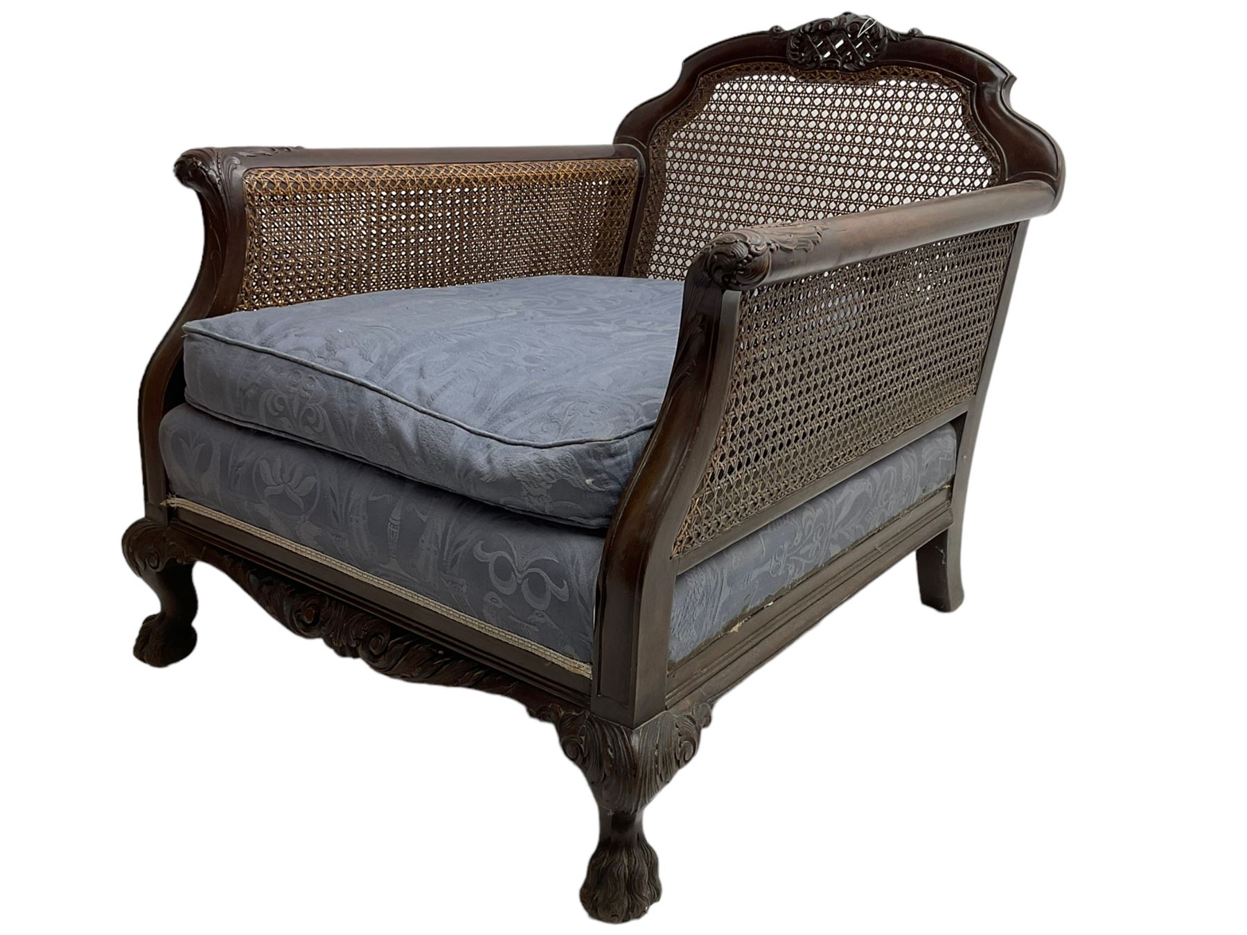 Early 20th century mahogany bergère armchair, the cresting rail carved with scrolled acanthus leaves over pierced lattice work, the arms carved with acanthus leaves, upholstered in blue fabric decorated with arches and birds and mythical Hippocampi, on hairy paw carved cabriole feet