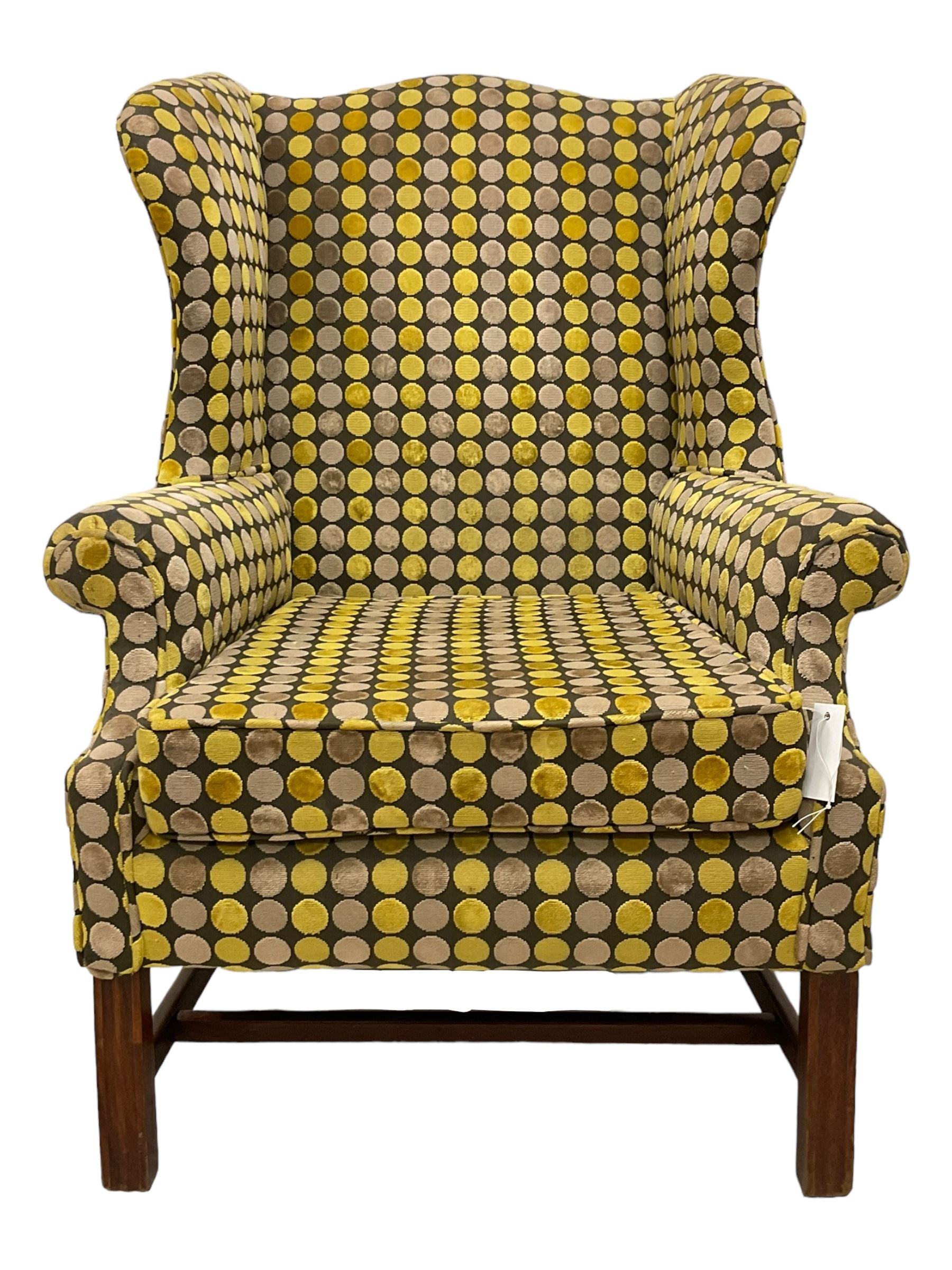 Georgian design mahogany framed wingback armchair, upholstered in spotted fabric in shades of grey and green, on moulded square supports united by stretchers 