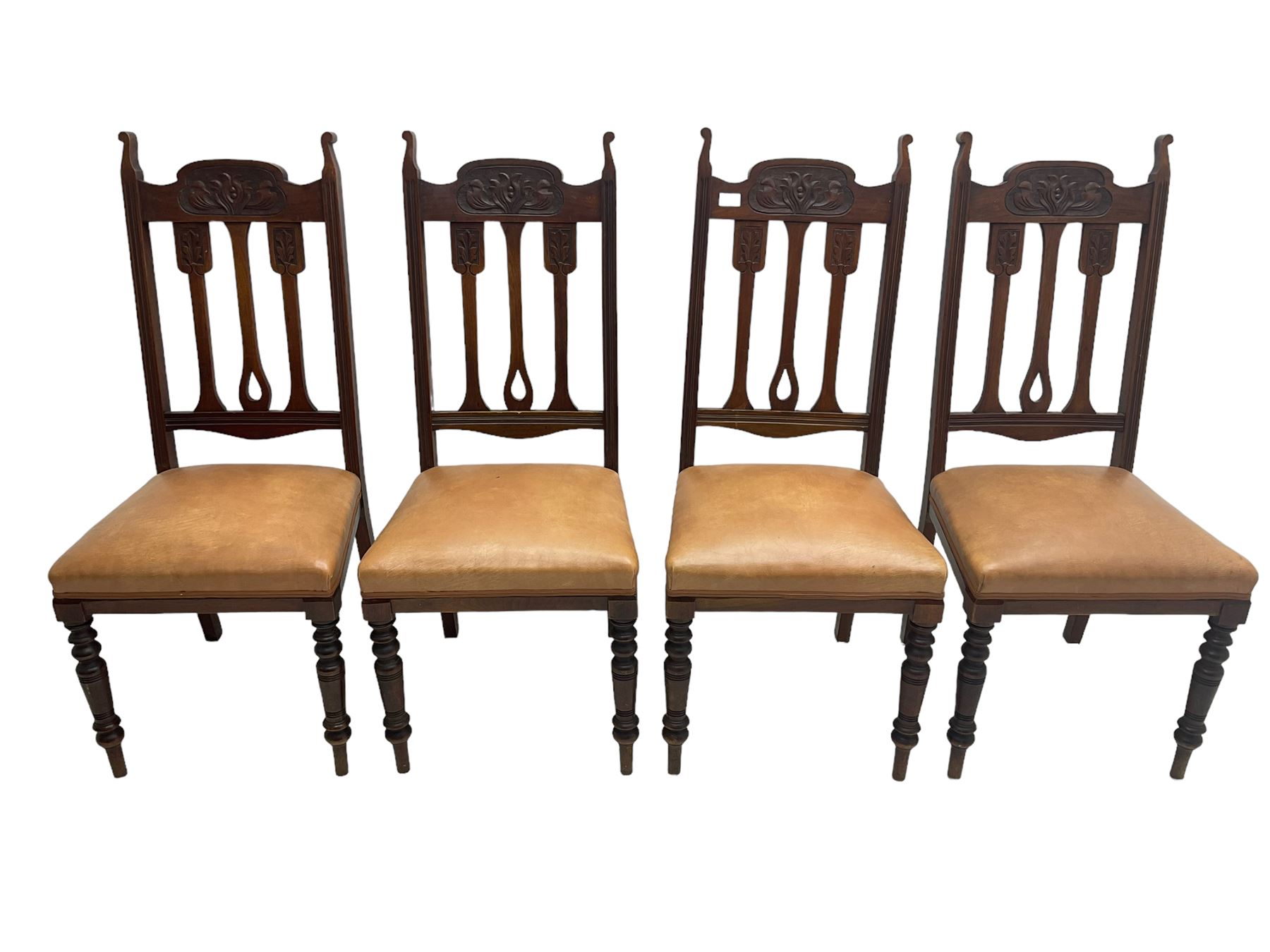 Set of four Edwardian walnut dining chairs, foliate carved high back over sprung seat upholstered in tan faux leather, raised on turned supports