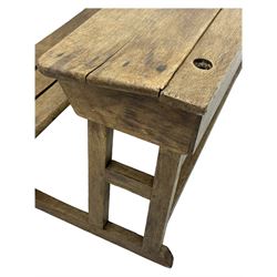 Victorian child's pine double school desk, the writing surface with two inkwells and two shelves underneath, integrated slatted bench seat raised on supports united by stretcher 