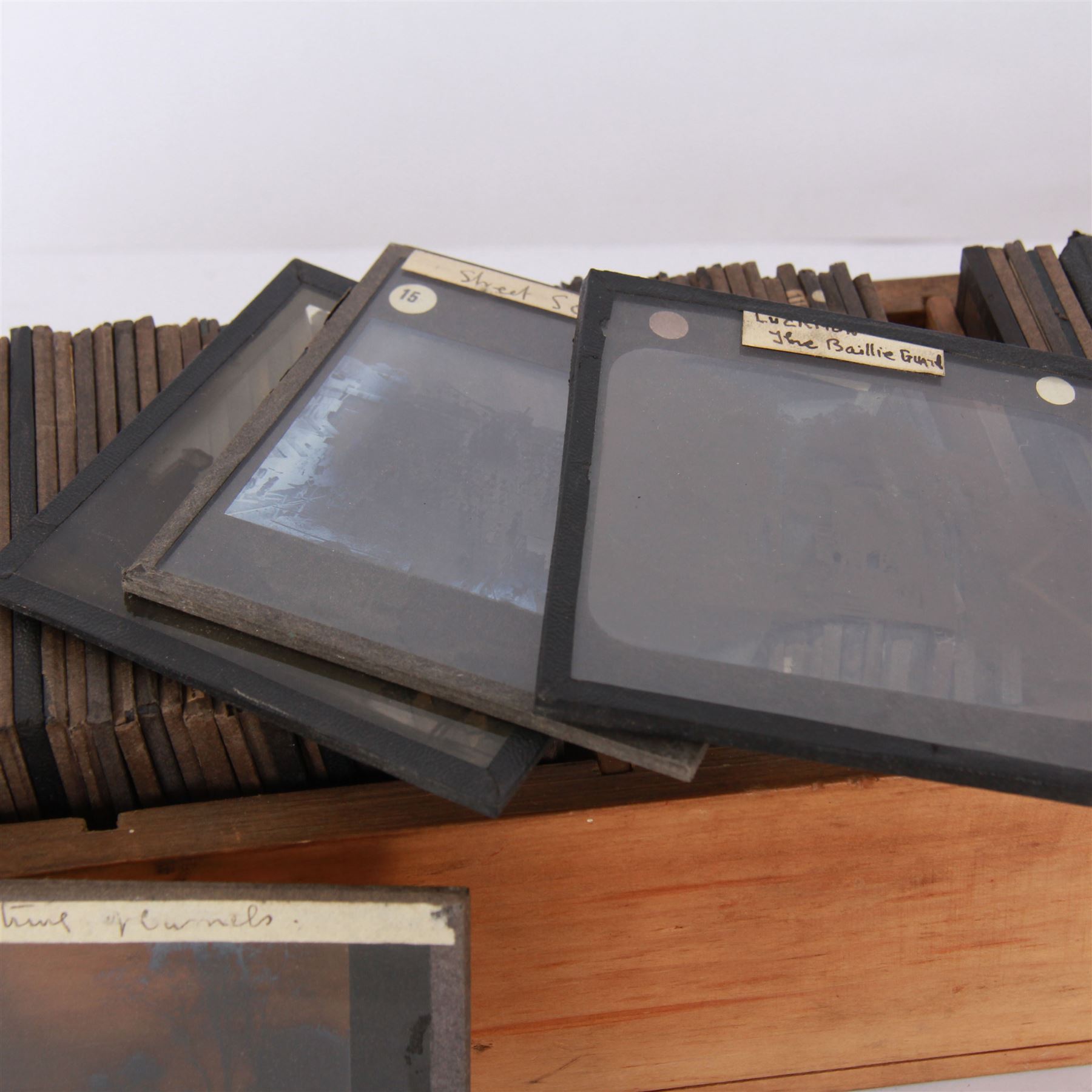 Collection of magic lantern slides, predominantly depicting views of India, with scenes including including the Taj Mahal, tombs, monuments, street scenes, people and animals, in compartmentalised wooden case 