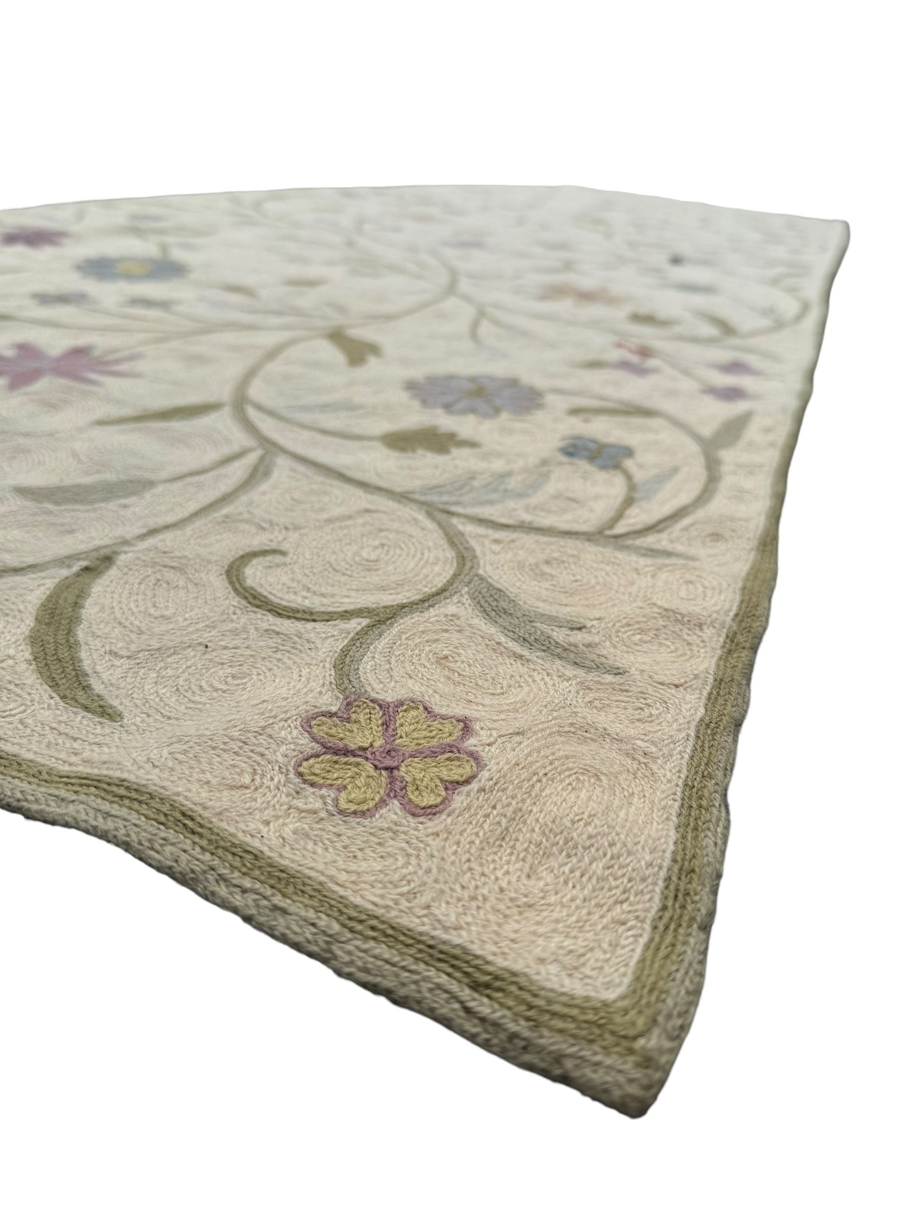 Kashmiri hand-stitched wool chain runner, featuring a cream ground decorated with meandering vines and an array of pastel flowers, enclosed by a plain light green border