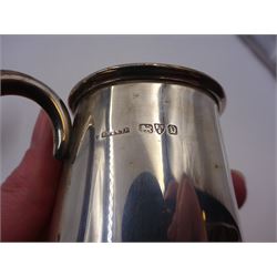 Two silver christening mugs, the first a Victorian example, of part fluted waisted form, upon circular foot with scroll handle, hallmarked Edward, John & William Barnard, London 1838, the second example of plain slightly tapering form with C handle, hallmarked S Blanckensee & Son Ltd, Chester 1929, tallest H9cm