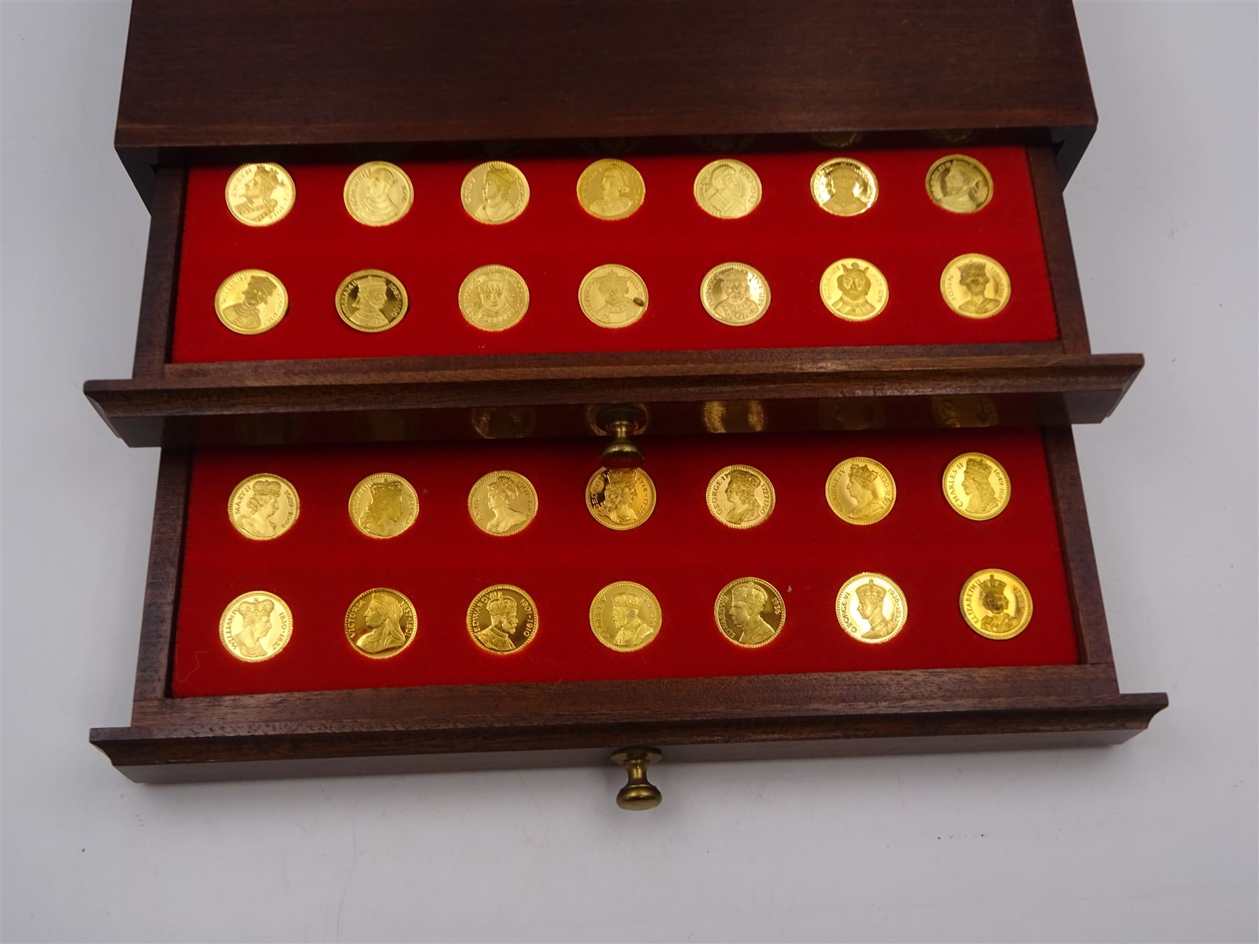 Danbury Mint, Our Royal Sovereigns Collection, seventy 22 carat gold plated silver medallions depicting the complete line of British monarchs to mark the 1200th anniversary of the first coronation, contained within wooden table top collectors cabinet with two drawers, with certificate of authenticity, with two drawers, hallmarked Danbury Mint, London various dates