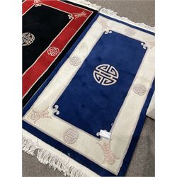 Collection of four Chinese washed woollen rugs - blue ground (153cm x 92cm); red and black ground (156cm x 94cm); light blue ground (138cm x 70cm); gold ground (153cm x 77cm)