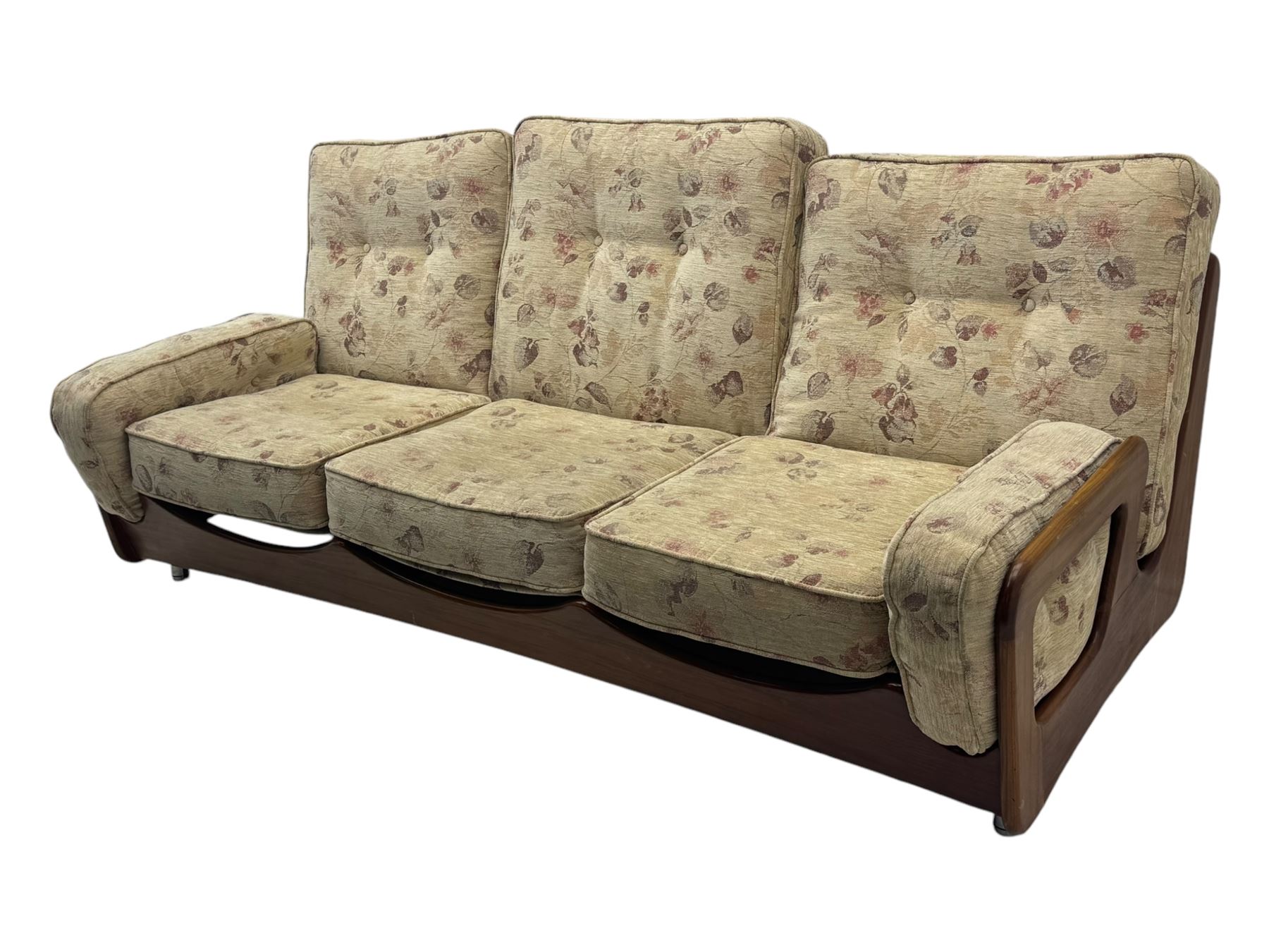 Mid-20th century three-seat sofa with floral patterned upholstery, supported by a sculpted teakwood frame with curved cutout detailing, loose cushioned back and seat, on tubular metal feet