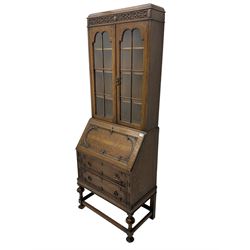 Early to mid-20th century oak bureau bookcase, blind fretwork frieze over two astragal glazed doors, the fall front with foliate carved brackets enclosing fitted interior, fitted with two drawers, on turned supports joined by moulded stretchers