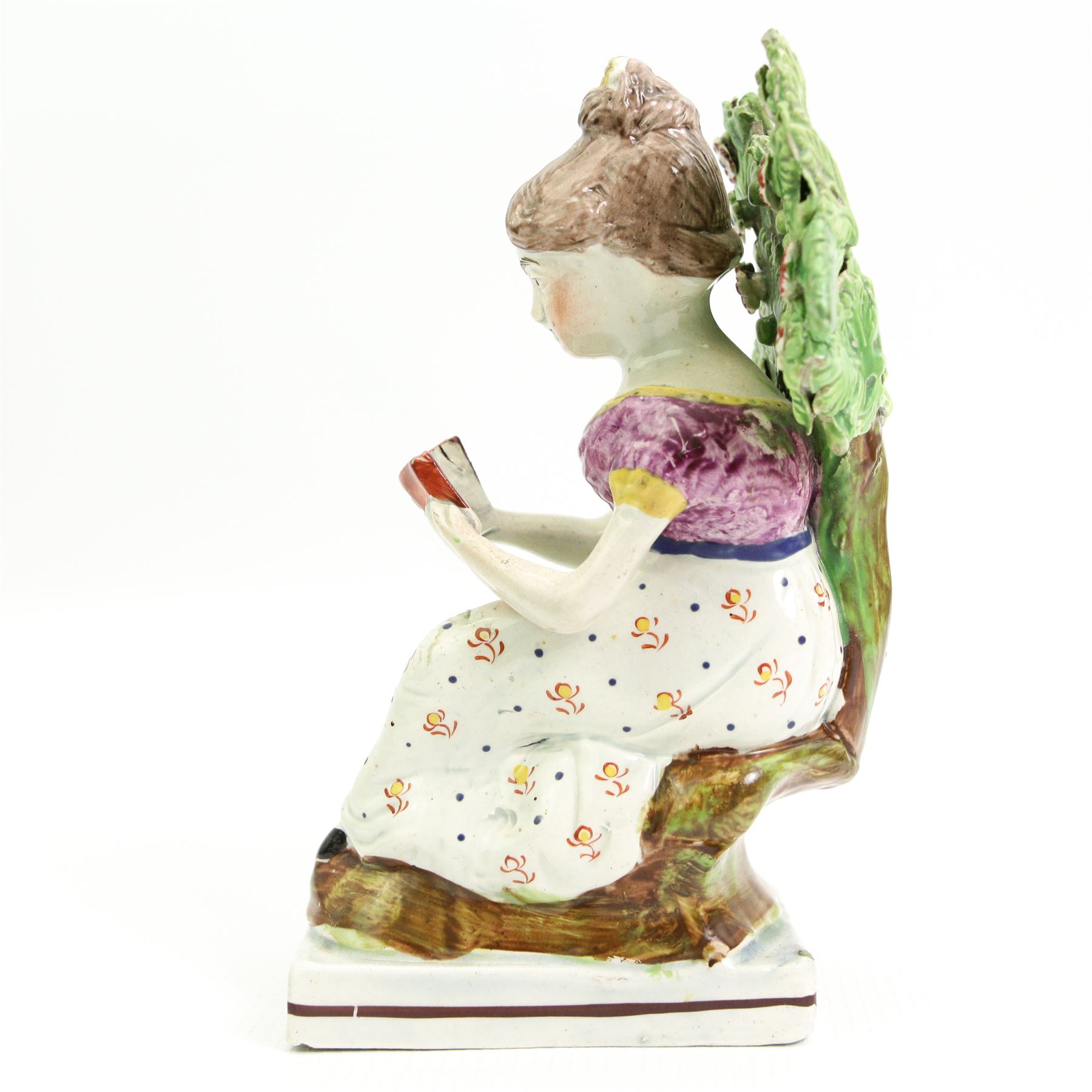 Early 19th century Staffordshire Pearlware figure 'The Reading Girl or Maid' of Obadiah Sheratt type, c1820-1830, modelled as a young woman seated by a tree reading a book, H16cm 