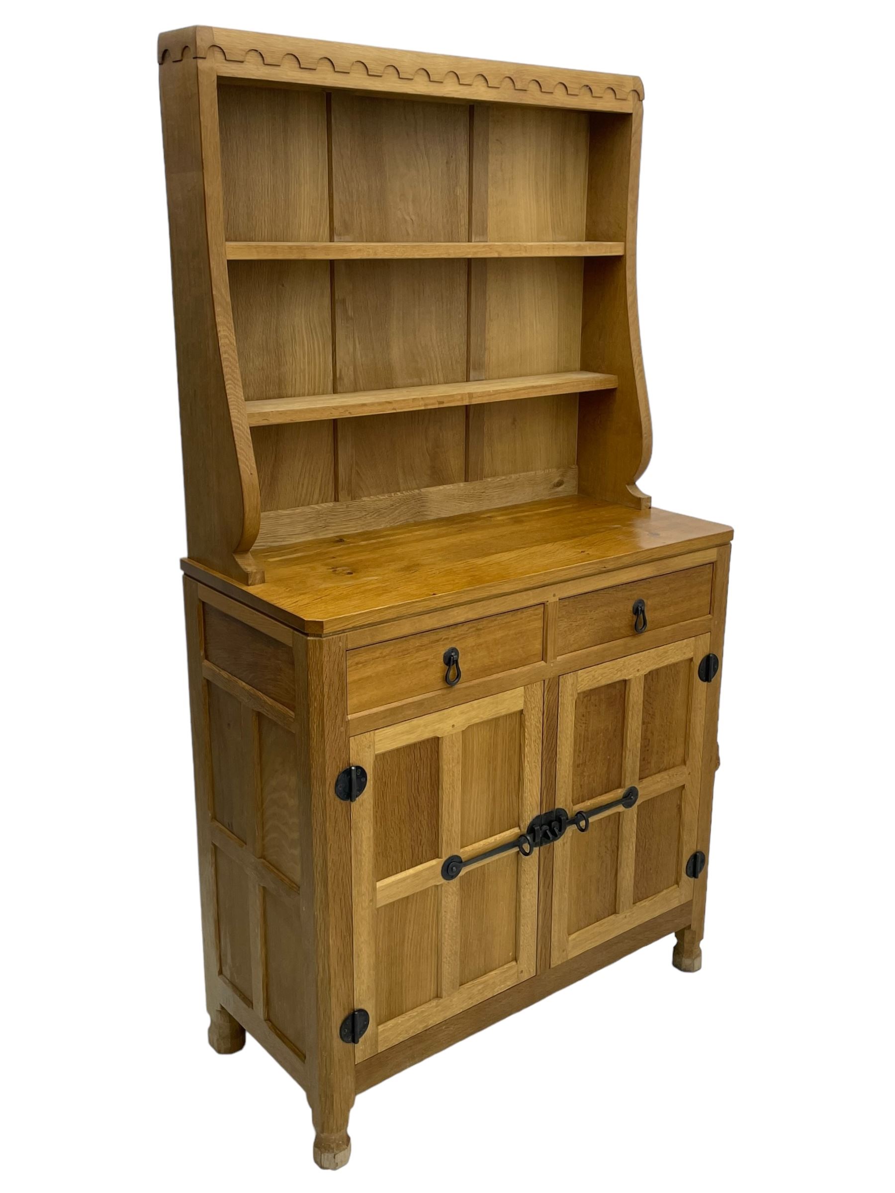 Mouseman - oak dresser, penny moulded cresting rail over two shelves supported by shaped ends, canted rectangular adzed top, fitted with two drawers and panelled cupboards, with wrought iron hinges and catches, on octagonal feet, carved with mouse signature, by the workshop of Robert Thompson, Kilburn 