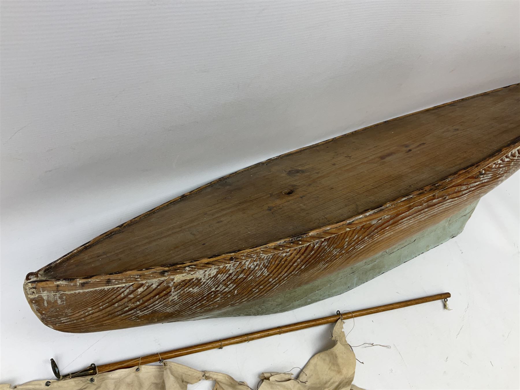 Early 20th century large pitch pine pond yacht hull painted light blue and white with lead keel and simulated planked deck L102cm; together with a two-piece wooden mast and sails
