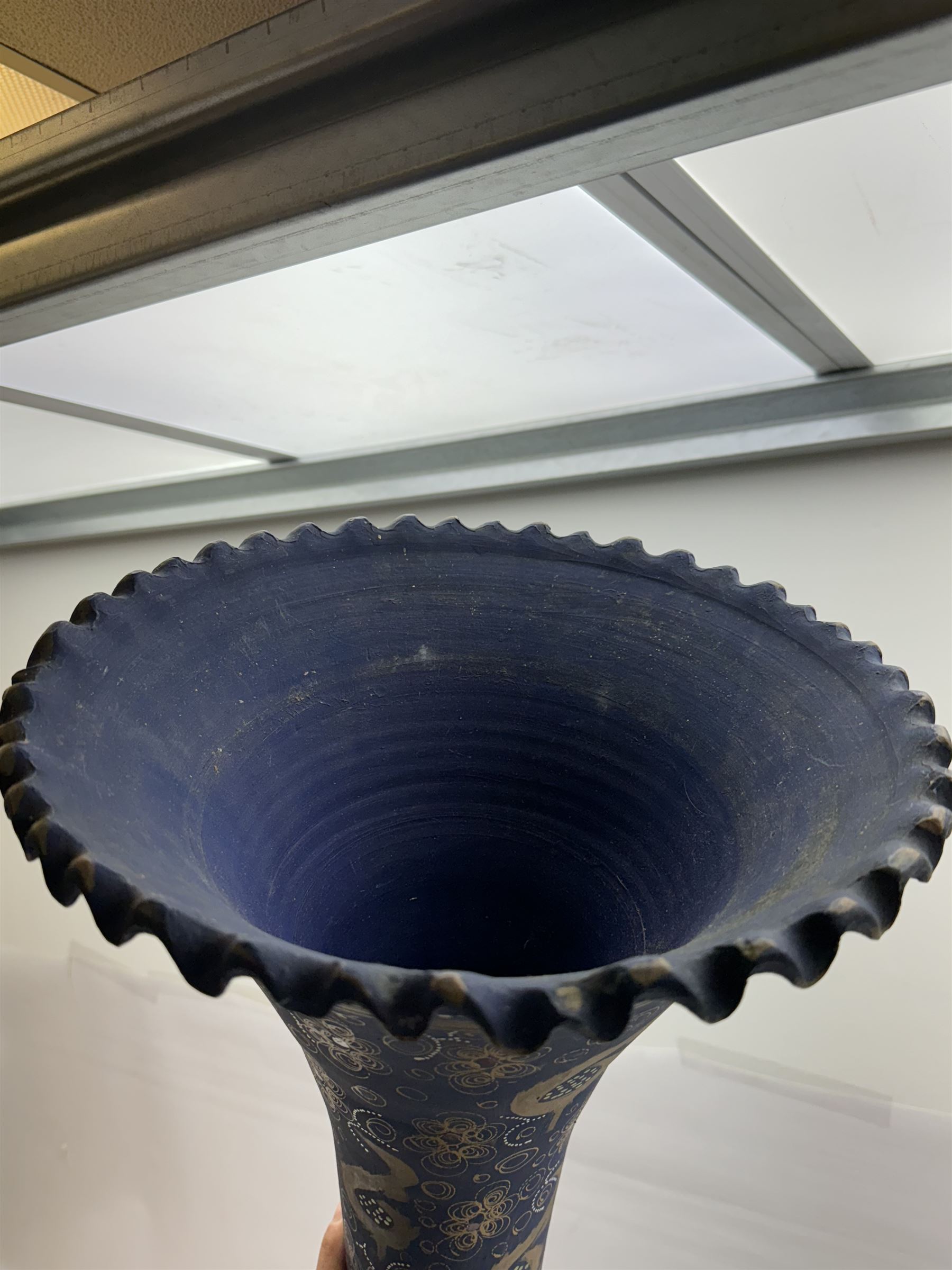 Large and unusual terracotta floor vase, of ovoid form with tall flared neck with frilled rim, decorated with stylised foliate motifs in gilt upon a dark blue ground, H89cm