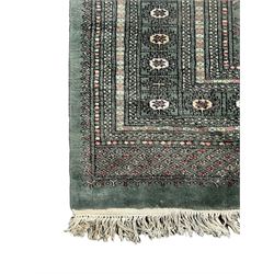 Pakistani Bokhara green ground rug, the field decorated with rows of repeating gul motifs, the main border featuring a series of smaller gul designs and geometric patterns, framed by multiple guard stripes