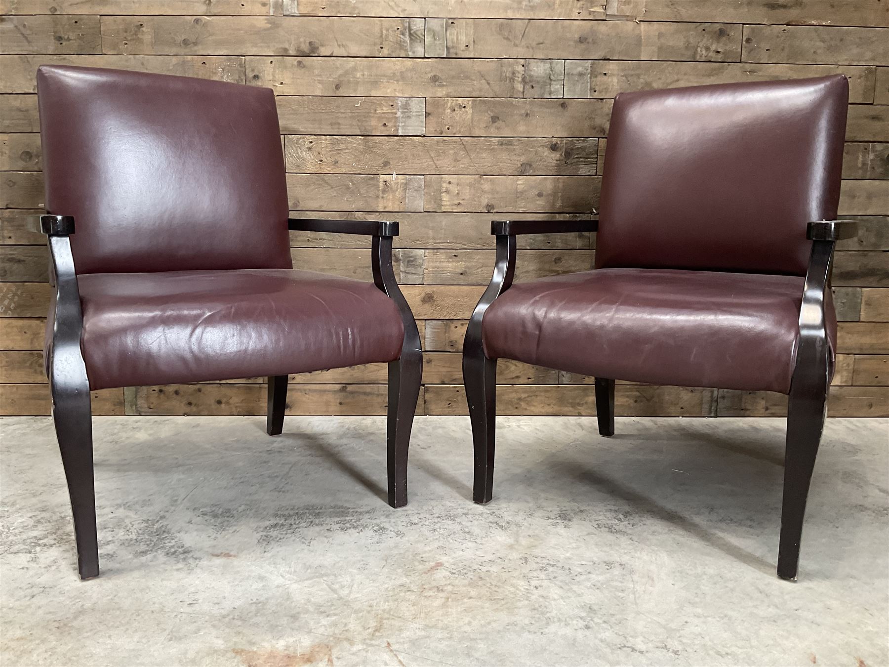 Two rosewood framed armchairs, upholstered in brown leather