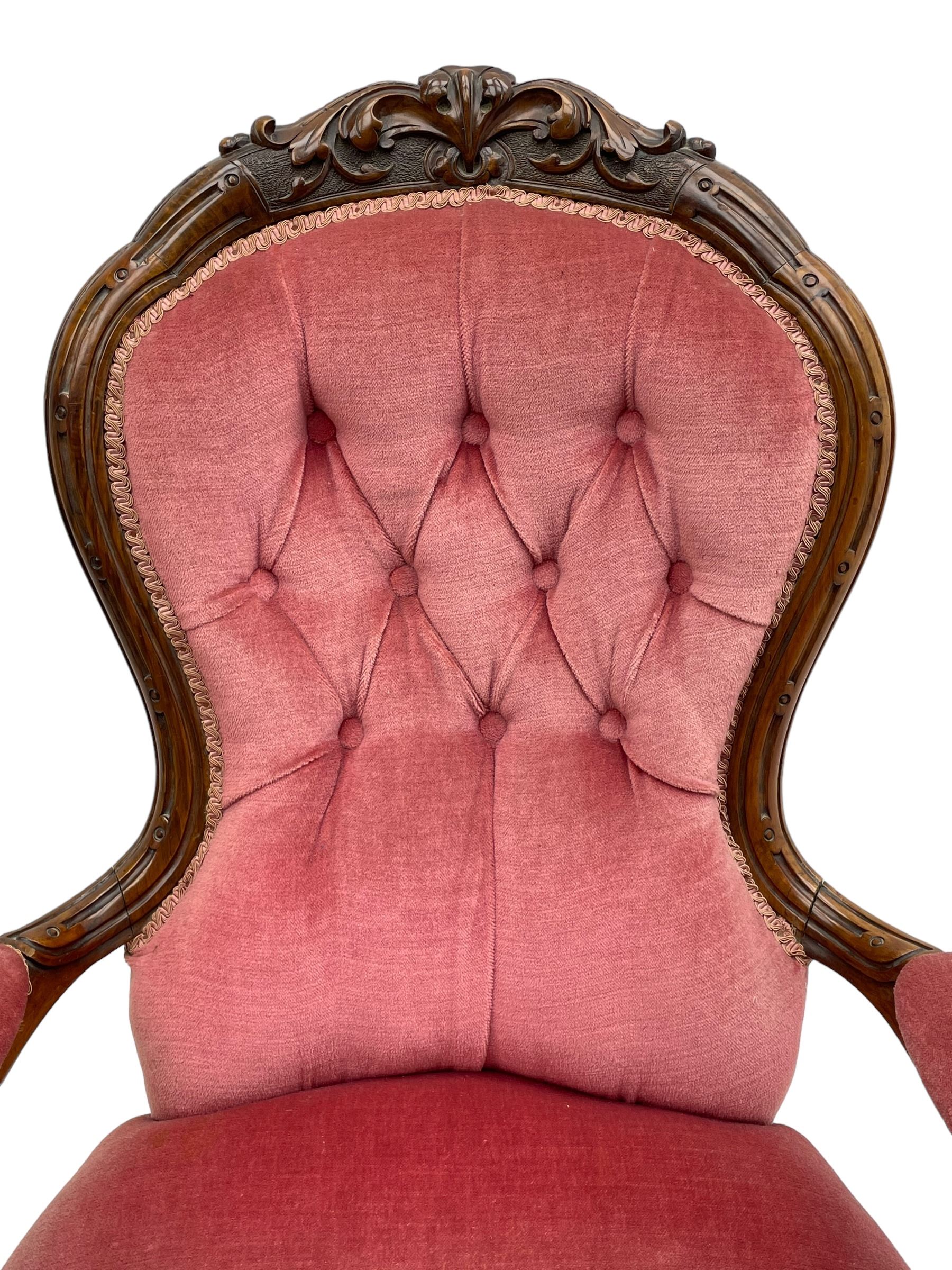 Victorian carved walnut open armchair, foliate carved cresting rail over butted back and sprung seat, upholstered in pink velvet scrolled arm terminals with moulded scrolling vines terminating to cabriole supports and ceramic castors